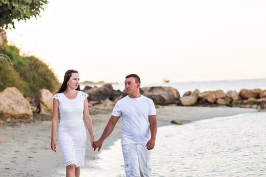 Happy couple walking together along the beach