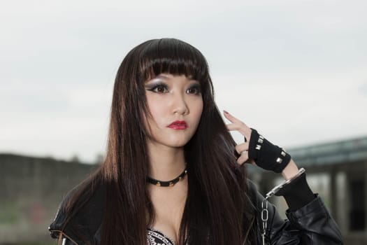 Asian American woman in emo goth clothing at an abandoned building