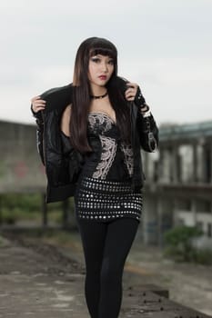 Asian American woman in emo goth clothing at an abandoned building