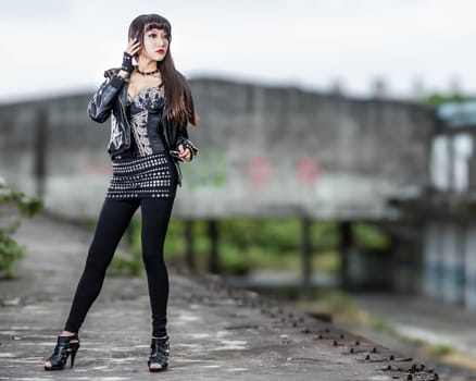 Asian American woman in emo goth clothing at an abandoned building