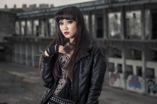 Asian American woman in emo goth clothing at an abandoned building