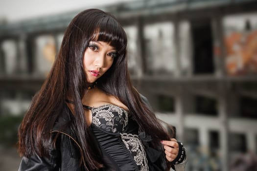 Asian American woman in emo goth clothing at an abandoned building