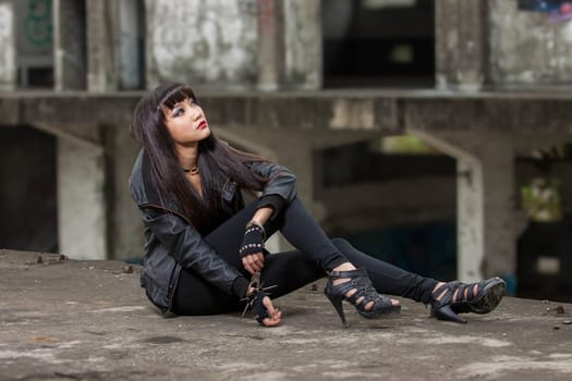 Asian American woman in emo goth clothing at an abandoned building