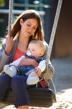 Woman, baby and swing on park for play, bonding and love with sunshine, child development and care. Mother, kid and infant swinging outdoor in summer for fun, enjoyment and nurture with happiness.