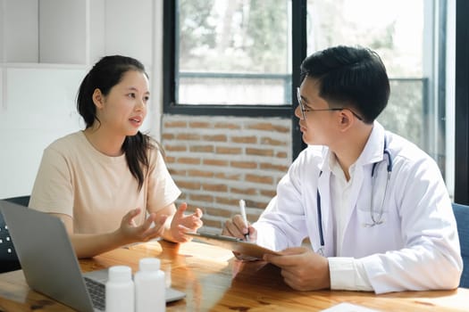Medicine, healthcare and people concept. A doctor explaining diagnosis to patient. The physician doctor listening to patient during consultation while sitting down in the office of a modern medical center..