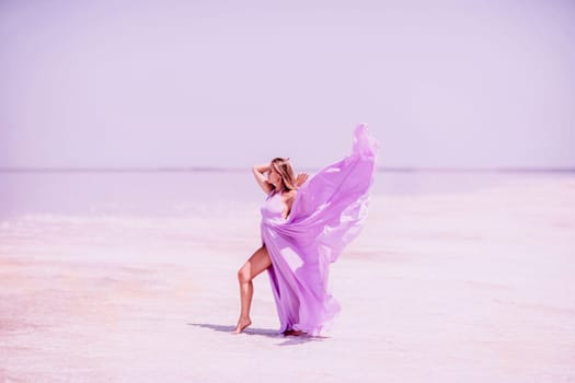 Woman pink salt lake. Against the backdrop of a pink salt lake, a woman in a long pink dress takes a leisurely stroll along the white, salty shore, capturing a wanderlust moment