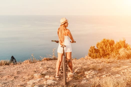 Woman travel bike sea. Happy woman cyclist sitting on her bike, enjoying the beautiful mountain and sea landscape, signifying the idea of an adventurous bike ride