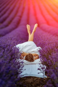 Woman lavender field. A middle-aged woman lies in a lavender field and enjoys aromatherapy. Aromatherapy concept, lavender oil, photo session in lavender.