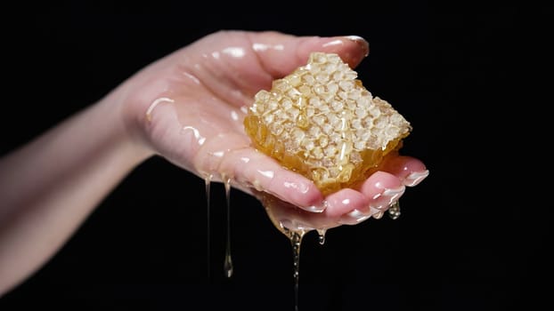 Woman hand with honeycombs full of honey. Dripping, pouring tasty sweet fluid. Thick golden flowing nectar. High quality photo
