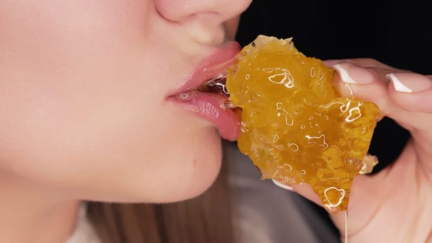 Woman eating honey with wax honeycomb. Close-up mouth. Healthy food ,natural sweets. Yummy background. High quality photo