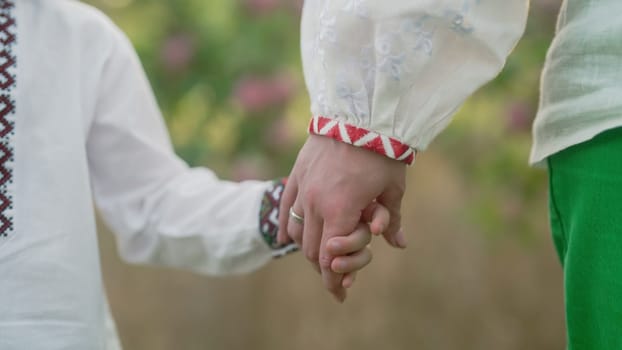 Ukrainian mom and child holding hands together, family background. Son takes mother hand. Trust, love and happiness concept