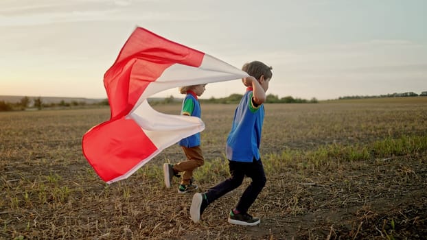 Polish little cute boys running with Poland national flag. Patriotism. Red and white colors, 11 November - Independence Day. Friends, brothers, happy future. High quality photo