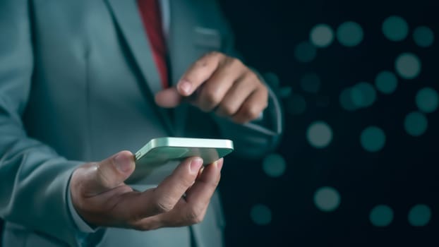 Close-up shot of businessman holding smartphone on dark background Represents business communication concepts.