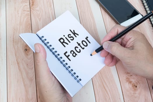 Businessman hands with pen writing notebook on office desk. Risk Factor. Business concept.