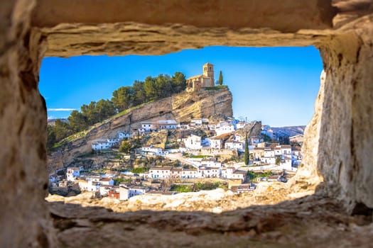 Scenic white village of Montefrio near Granada view through stone window, Andalusia region of Spain