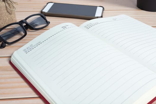 View of office desk with smartphone, reading glasses and and notepad. Copy space.
