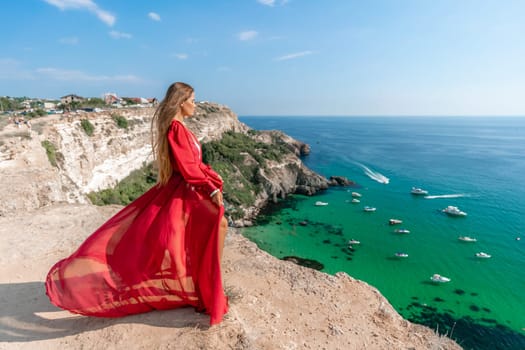 Red Dress Woman sea Cliff. A beautiful woman in a red dress and white swimsuit poses on a cliff overlooking the sea on a sunny day. Boats and yachts dot the background