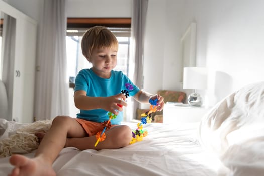 A little boy sitting on a bed playing with a toy
