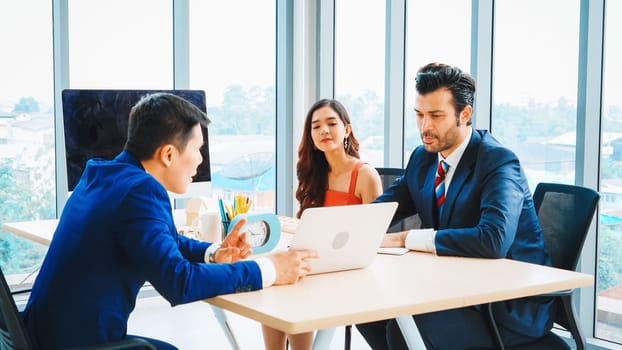 Smart businessman and businesswoman talking discussion in group meeting at office table in a modern office interior. Business collaboration strategic planning and brainstorming of coworkers. Jivy