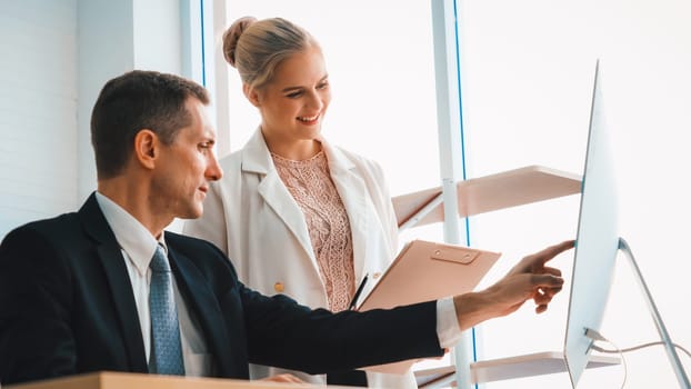 Two business people talk project strategy at office meeting room. Businessman discuss project planning with colleague at modern workplace while having conversation and advice on financial report. Jivy