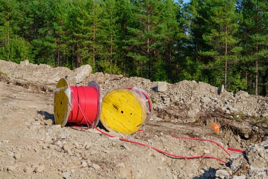 Wooden Reel with High Voltage Red Cable in Forest: Ready for Underground Power Line Installation, in forest