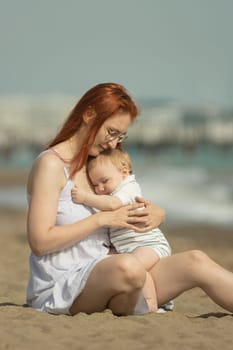 Happy mother and her little son resting on the seaside - hugging. Mid shot
