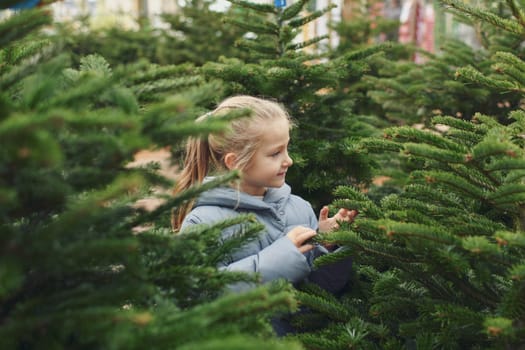 Small girl chooses a Christmas tree in the shop.