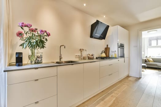 a kitchen with flowers on the counter and tv mounted to the wall in the living room next to the dining area