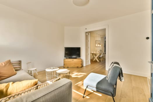 a living room with white walls and hardwood flooring, including a grey sofa set in the center of the room