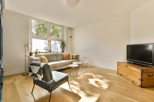 a living room with wood flooring and a flat screen tv mounted on the wall in front of the couch