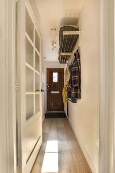 a hallway with clothes hanging on the wall and an open door leading to another room that has wood flooring