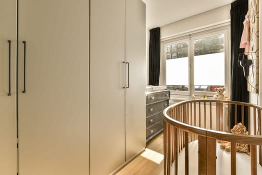 a kitchen with white cupboards and wooden flooring in the center of the room, there are black curtains on the windows