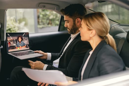 Cheerful business people have online meeting using laptop while sitting in car back seats