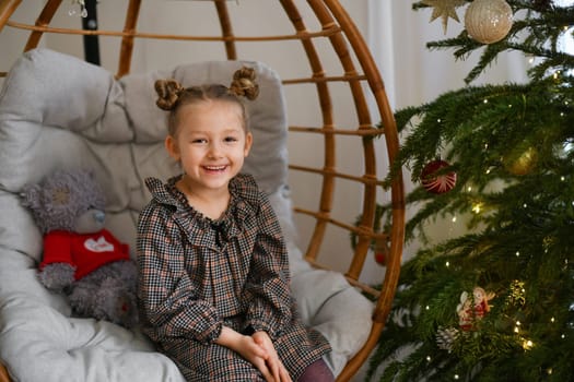 Girl in a suspended chair near the Christmas tree