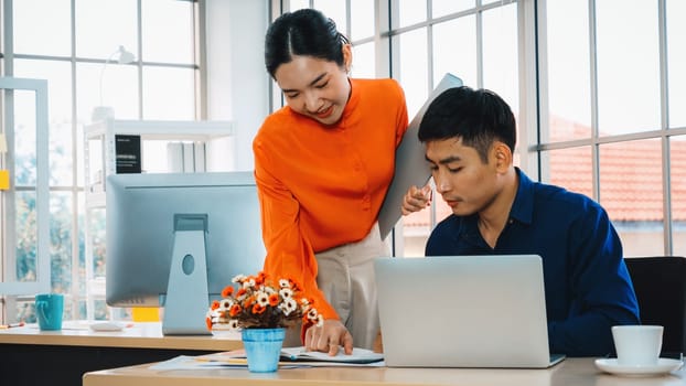 Two business people talk project strategy at office meeting room. Businessman discuss project planning with colleague at modern workplace while having conversation and advice on financial report. Jivy