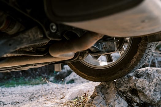 View from under the bottom of a car standing with a wheel on a rock ledge. High quality photo