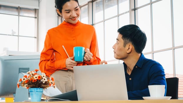 Two business people talk project strategy at office meeting room. Businessman discuss project planning with colleague at modern workplace while having conversation and advice on financial report. Jivy