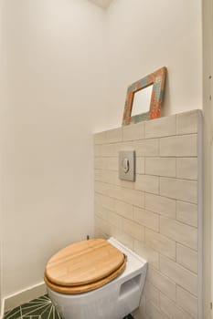 a toilet in the corner of a bathroom with green tiles on the floor and white walls, along with a wooden toilet seat