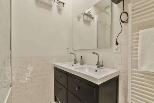 a bathroom with black cabinets and white tiles on the walls, along with a large mirror in the shower stall