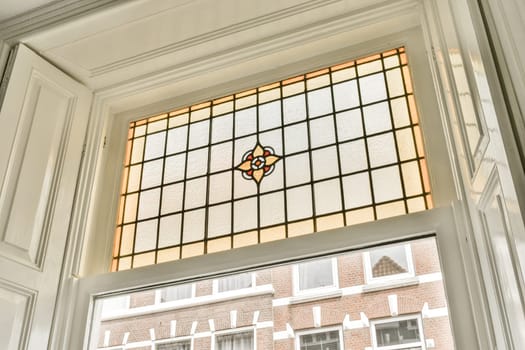 a stained glass window in a house with white trim on the windowsills, and a brick wall behind it