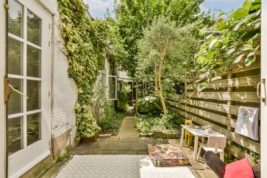 a back yard with lots of plants on the walls, and an open door leading to a small patio area