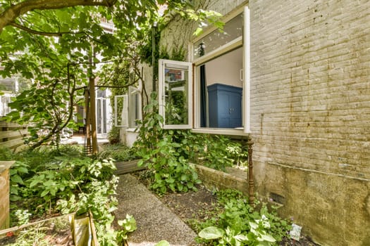 the outside of a house with plants growing in front and an open window on the other side of the house