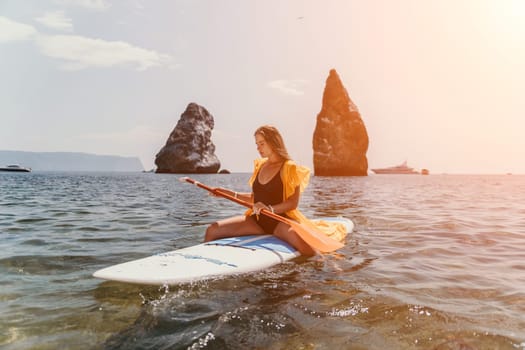 Close up shot of beautiful young caucasian woman with black hair and freckles looking at camera and smiling. Cute woman portrait in a pink bikini posing on a volcanic rock high above the sea