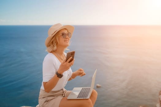 Freelance women sea. She is working on the computer, talking on the phone in the open air with a beautiful view of the sea. The concept of remote work