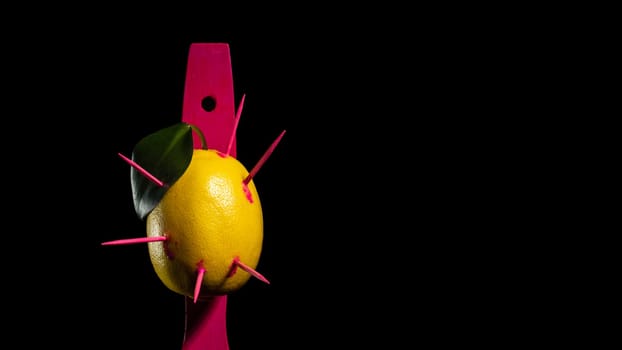 Creative still life with lemon struck by arrows on a black background