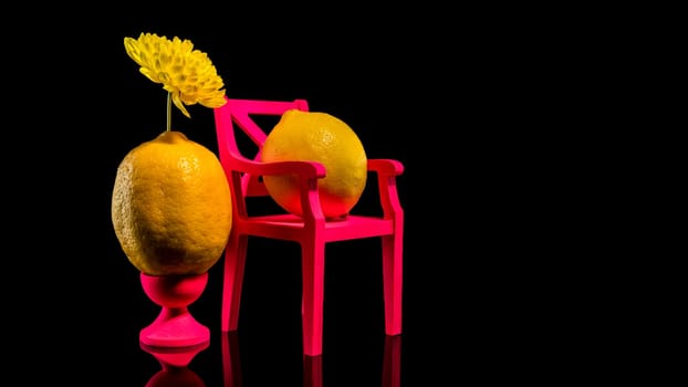 Creative still life with two lemons and pink chair on a black background