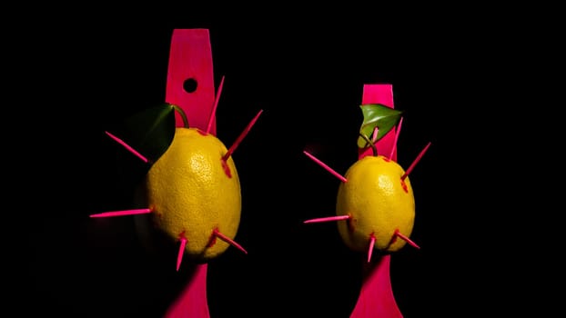 Creative still life with two lemons struck by arrows on a black background