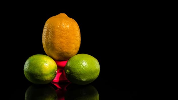 Creative still life with lemon and two limes on a black background