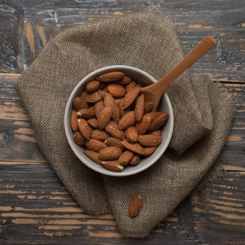 Almonds in a bowl on a wooden background