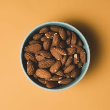 Almonds in a bowl on a yellow background